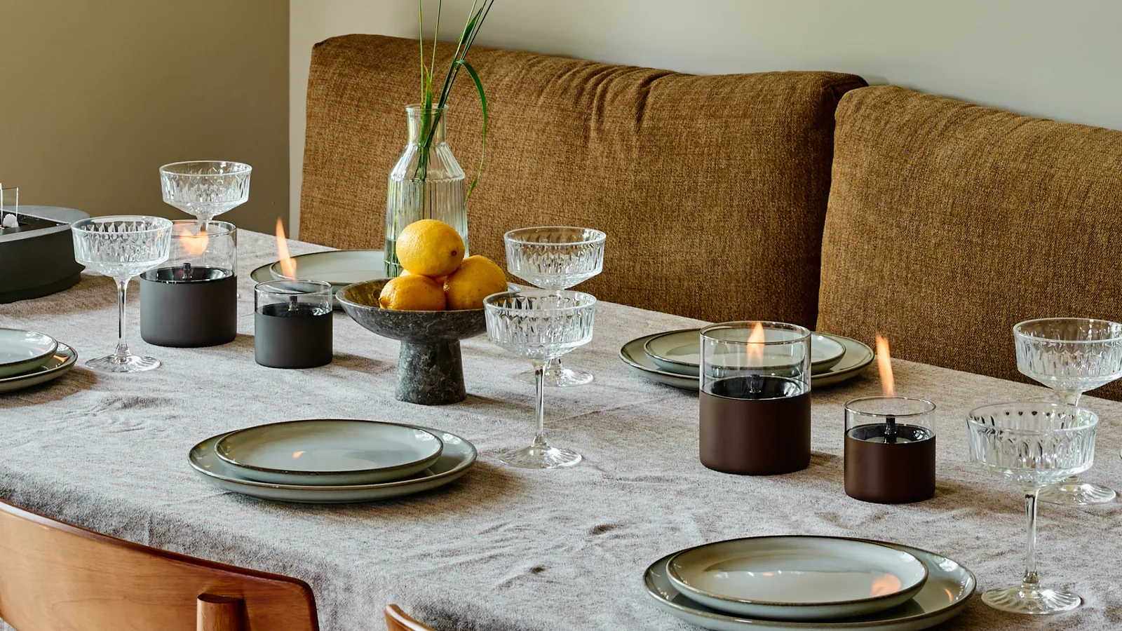 A laid dining table with several lit Tenderflame table fireplaces